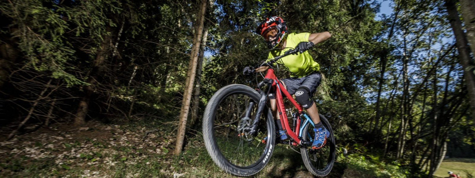 Springender Mounainbiker auf einer Trailpassage im Wald am Weissensee