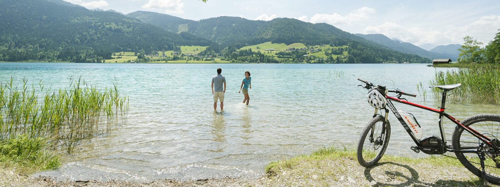 Paar im Wasser mit Mountainbike im Vordergrund am Weissensee