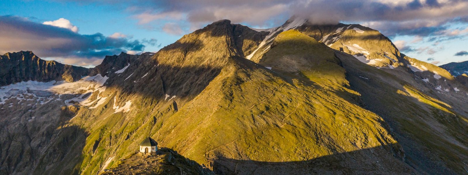 Die Kapelle auf der Arnoldhöhe oberhalb der Bergstation. Im Wolken im Hintergrund der Ankogel (3.252 m)